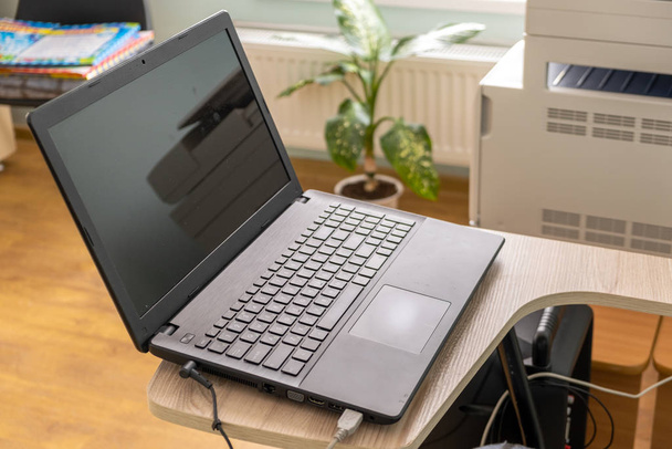 Open zwarte laptop computer op een kleine stoel tafel in kantoor inte - Foto, afbeelding