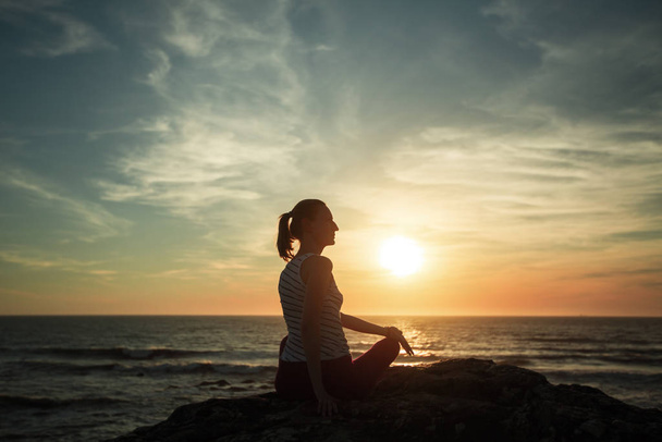 Silhouette Frau praktiziert Yoga am Strand bei Sonnenuntergang. - Foto, Bild