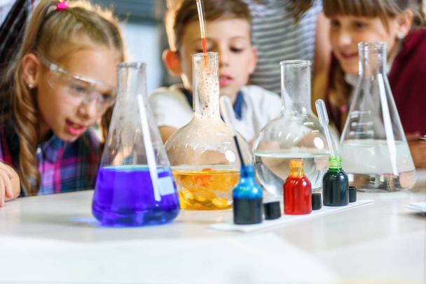 Test tubes with colorful liquid substances. Study of liquid states. Group school pupils with test tubes study chemical liquids. Science concept. Girls and boy providing experiment with liquids. - Foto, immagini