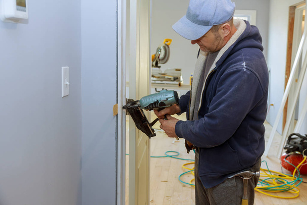 Κατασκευή εσωτερικό εγκαταστήστε την πόρτα νέο ξυλουργός σπίτι χρησιμοποιώντας το πιστόλι καρφί αέρα - Φωτογραφία, εικόνα