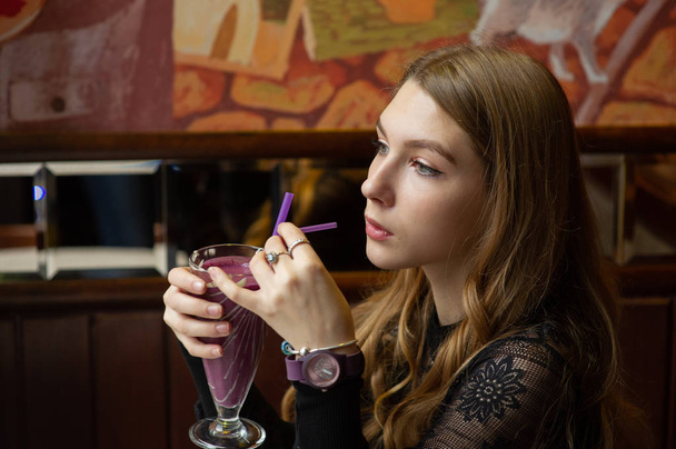 Mädchen im schwarzen Kleid mit einem Cocktail in einem Café - Foto, Bild