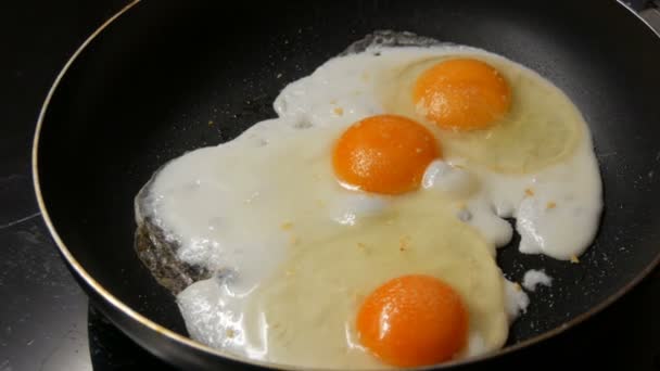 Detailní pohled na smažená vejce v pánvi posypaná kořením - Záběry, video