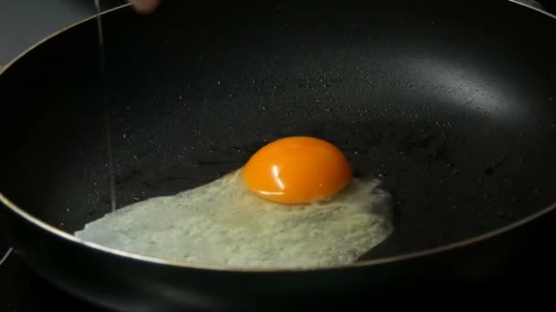 Erkek aşçı yumurta pişirmek için tavada yumurta kırıyor. - Video, Çekim
