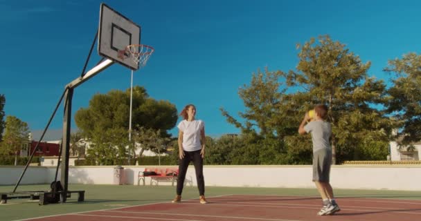 Οικογένεια παίζει μπάσκετ στο γήπεδο του αθλητισμού. - Πλάνα, βίντεο