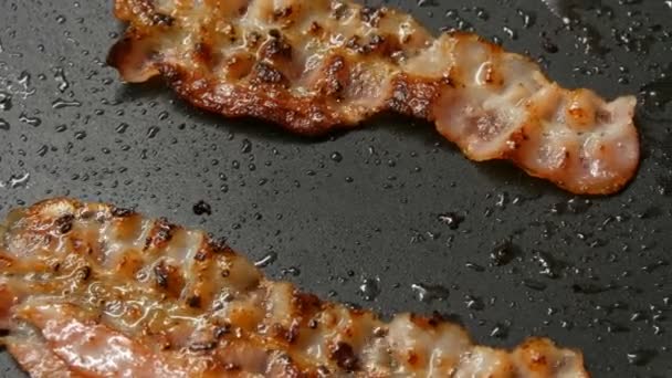 Três fatias de bacon fresco fritam-se na gordura na panela
 - Filmagem, Vídeo