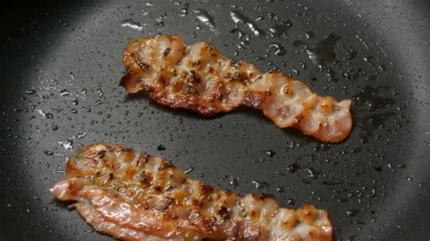 Tři plátky čerstvé slaniny jsou smažené na pánvi. - Záběry, video