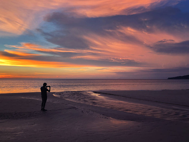 Πανοραμική θέα του ηλιοβασιλέματος ένας άνθρωπος που παίρνει φωτογραφία στην παραλία του Καρόν στο Ph - Φωτογραφία, εικόνα