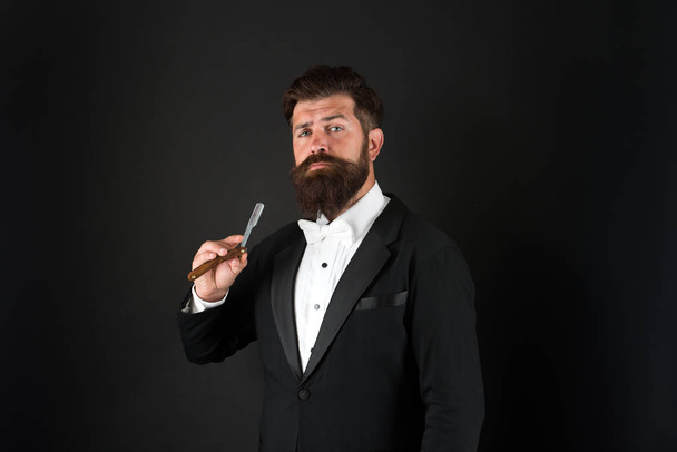 Real style for real man. Bearded man hold straight razor. Professional man with long mustache and beard hair. Brutal man in tuxedo suit. Hipster with formal look. Barbershop. November for facial hair - Photo, image