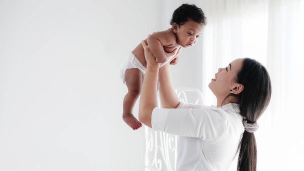 portrait of asian mother and her black mixed race baby girl in w - Photo, Image