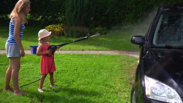 Happy mother and daughter washing car automobile in garden yard - Footage, Video