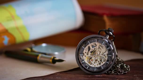 Карманные часы со старыми книгами и ручкой с бумажной картой на столе у окна. Концепция планирования поездок
. - Кадры, видео