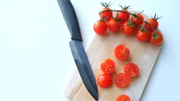 Couteau de cuisine élégant en céramique et petites tomates cerises rouges mûres en bouquet de grappes et partiellement coupées sur le tableau de cuisine
 - Séquence, vidéo