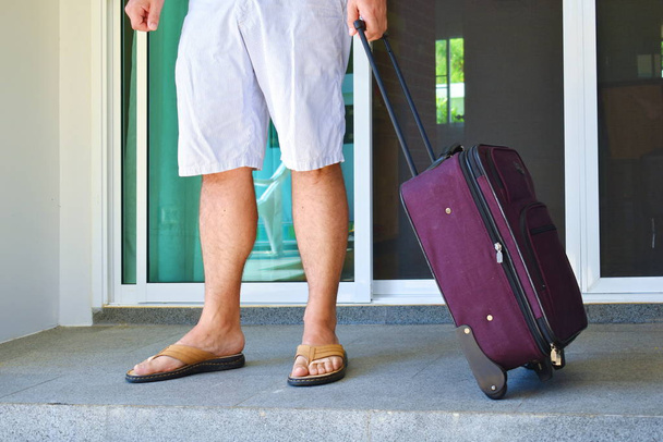 Man with travel suitcase at the door. To send on a journey. - Foto, Imagen