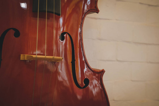 bruine cello bij rode muur. muziekinstrument - Foto, afbeelding