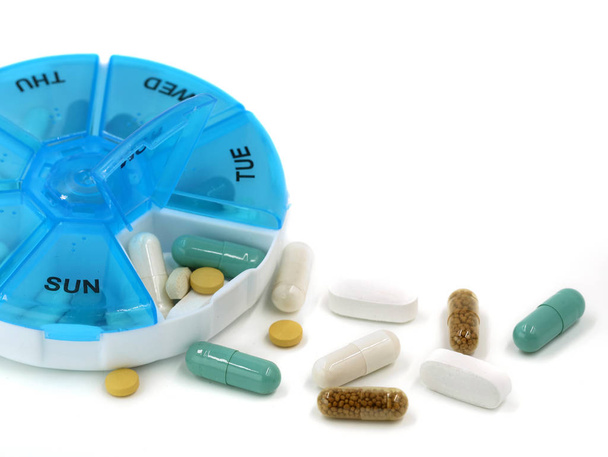 Gros plan de diverses pilules dans une boîte à pilules quotidienne sur fond blanc avec espace de copie
 - Photo, image