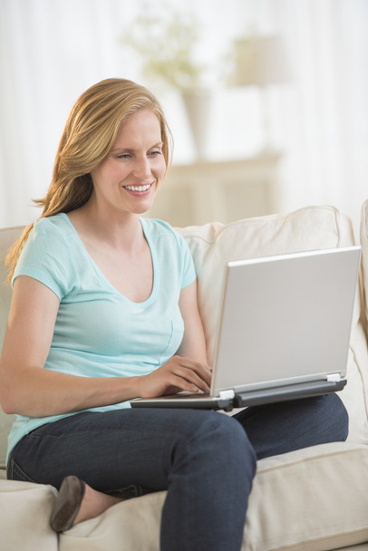 Woman Using Laptop While Sitting On Sofa - Foto, imagen