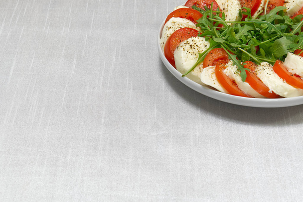 Mozzarella-Scheiben, Tomaten und Rucola auf dem Tisch. Mozzarella und Tomaten gestapelt in einem Teller mit Platz für Text. - Foto, Bild