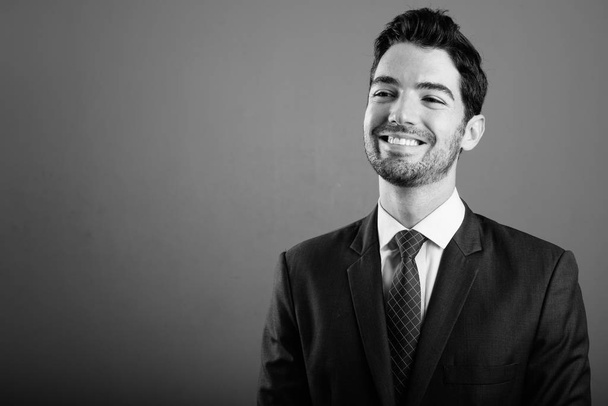 junger gutaussehender Geschäftsmann im Anzug vor grauem Hintergrund - Foto, Bild
