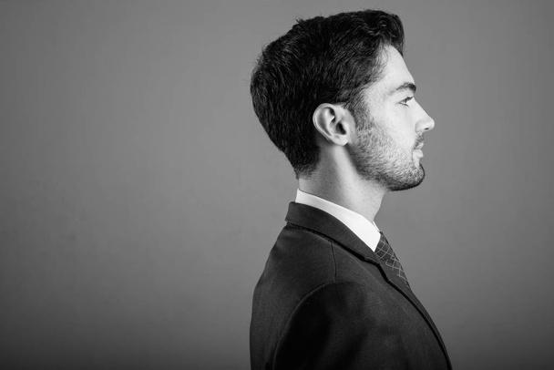 Giovane uomo d'affari bello in giacca e cravatta contro sfondo grigio
 - Foto, immagini