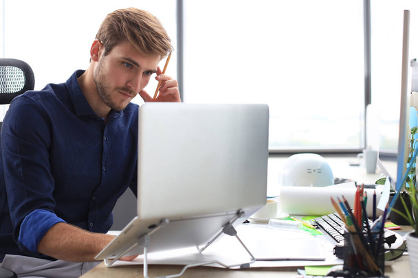 Elegant modern businessman analyzing data while working in office - Фото, изображение