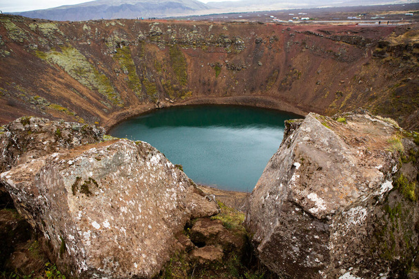 Jezioro krateru wulkanicznego Kerid na Islandii. Krajobraz z czerwonymi kamieniami wulkanicznymi na szczycie krateru Kerid z niebieskim jeziorem kraterowym na Islandii - Zdjęcie, obraz