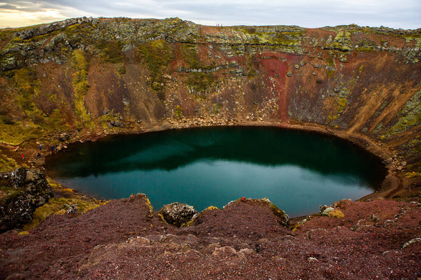 Kerid volcanic crater lake in Iceland. Landscape with red volcanic stones on the top of Kerid Crater with blue crater lake in Iceland - Fotó, kép