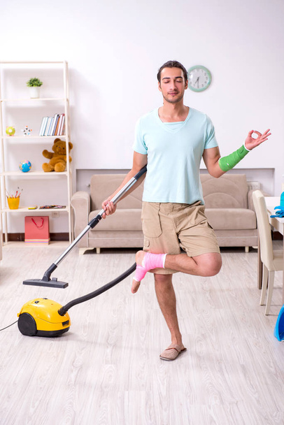 Young injured man cleaning the house - Foto, afbeelding