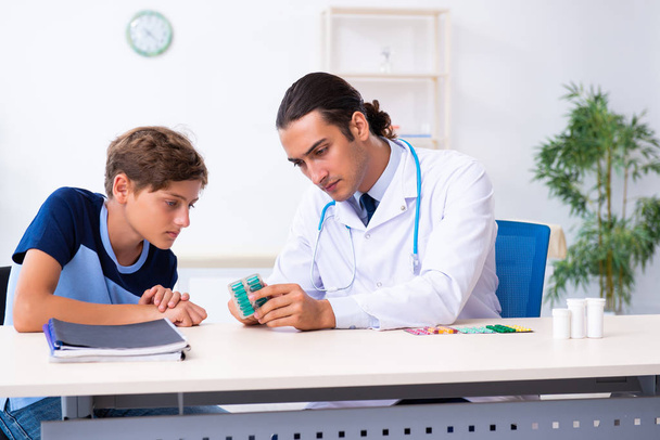 Jonge mannelijke arts onderzoeken jongen in de kliniek - Foto, afbeelding