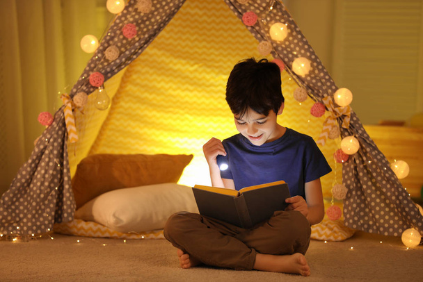 Preteen boy with flashlight reading book at home - Photo, Image