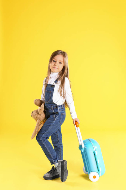 Cute little girl with suitcase on yellow background - Φωτογραφία, εικόνα
