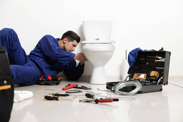 Professional plumber working with toilet bowl in bathroom - Foto, imagen