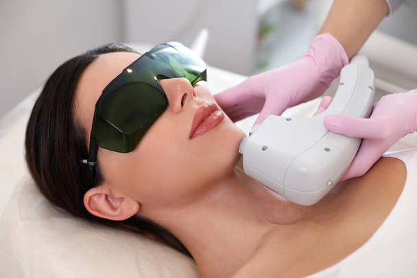 Young woman undergoing laser epilation procedure in beauty salon - Foto, Imagem