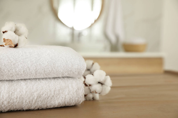 Pilha de toalhas limpas e flores de algodão na mesa de madeira no banho
 - Foto, Imagem