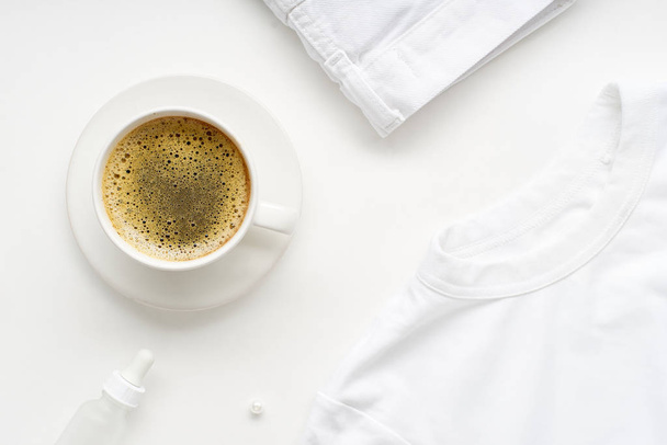 Creative flat lay with monochromatic white clothes and accessories with cup of coffee on white background. No stain concept                                - Foto, Imagem