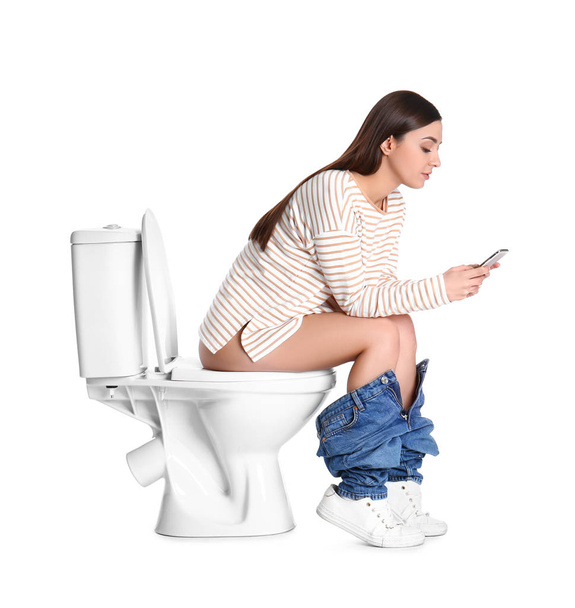 Woman with smartphone sitting on toilet bowl, white background - Foto, afbeelding