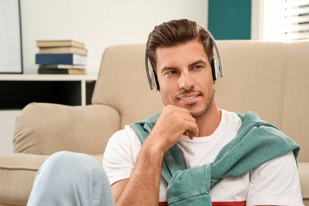 Man listening to audiobook near sofa at home - Fotó, kép
