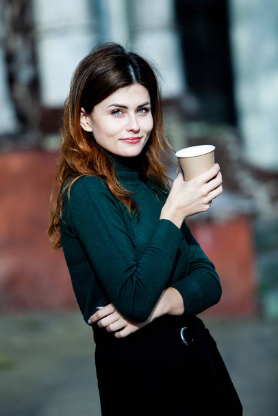 Mulher elegante jovem bebendo chá em uma rua da cidade. Hipster menina europeia com vidro de papel latte na rua. Linda jovem com xícara de café na rua da cidade. Pausa para café. Café para levar
.  - Foto, Imagem
