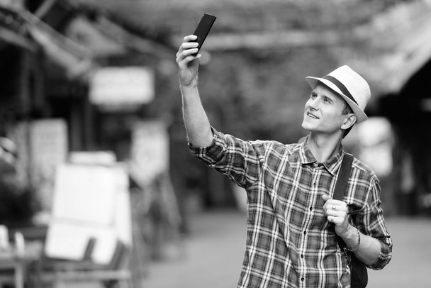 Giovane uomo turistico felice prendendo selfie con il telefono per le strade all'aperto
 - Foto, immagini