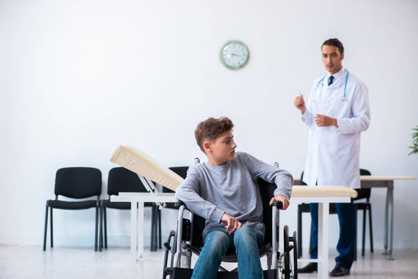 Jeune homme médecin pédiatre et garçon en fauteuil roulant
 - Photo, image