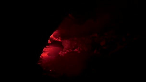 Męska sylwetka w podziemnej opuszczonej krypcie z rozbłyskiem czerwonego sygnału. Materiał filmowy. Człowiek kucki przed jaskinią w całkowitej ciemności. - Materiał filmowy, wideo