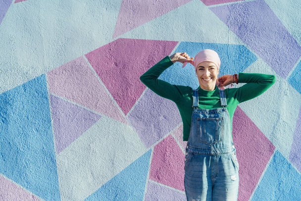 Vrouw met hoofddoek tegen kanker op een kleurrijke muur - Foto, afbeelding