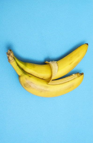 two bananas isolated on blue background. Love and tenderness. sign, symbol, concept of embracing couple - 写真・画像