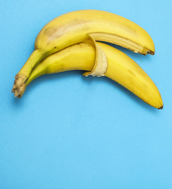 two bananas isolated on blue background. Love and tenderness. sign, symbol, concept of embracing couple - Photo, Image