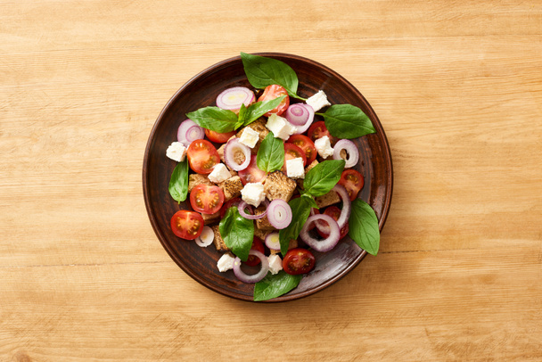 top view of fresh Italian vegetable salad panzanella served on plate on wooden table - Photo, Image