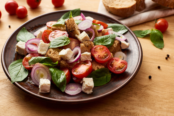 Lezzetli İtalyan sebze salatası panzanella taze malzemelerin yanında ahşap masada servis edilir. - Fotoğraf, Görsel