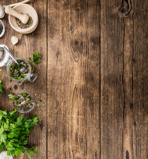Chimichurri on an old wooden table (selective focus) - 写真・画像