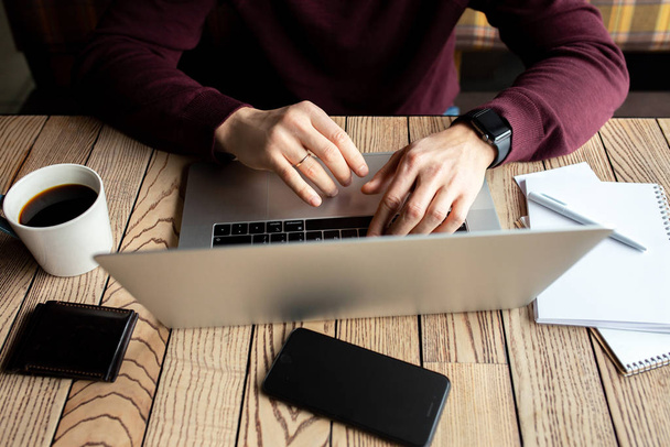 Man Working Laptop Connecting Networking Concept. El hombre está trabajando. Las manos están escribiendo en un teclado. Empresario con portátil, bloc de notas y bolígrafo en una mesa de madera en una cafetería con una taza de café
. - Foto, Imagen