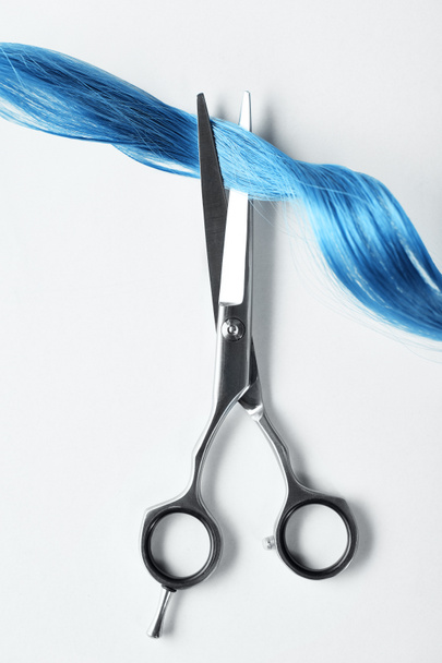 Draufsicht auf Schere und Locken aus blauem Haar auf weißem Hintergrund - Foto, Bild