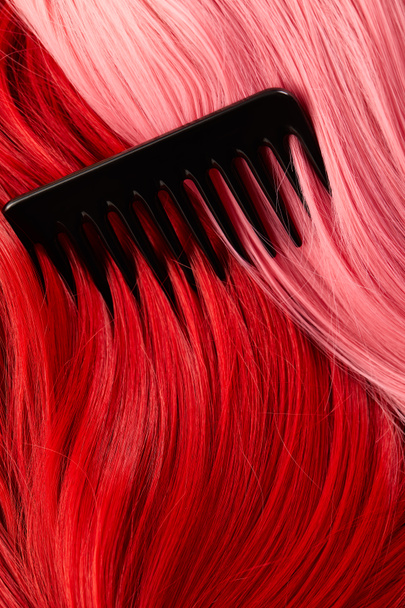 Kamm auf farbigem rosa und rotem Haar  - Foto, Bild