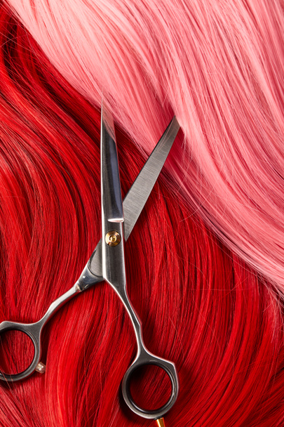 Top view of scissors on colored pink and red hair   - Φωτογραφία, εικόνα